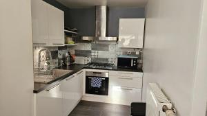 La cuisine est équipée de placards blancs et d'un four avec plaques de cuisson. dans l'établissement Appartement en duplex agréable à Élancourt, à Élancourt