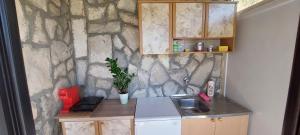 a small kitchen with a stone wall at Guest House Vodica in Virpazar