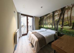 a bedroom with two beds with trees mural on the wall at Hotel Rural Milaleku 