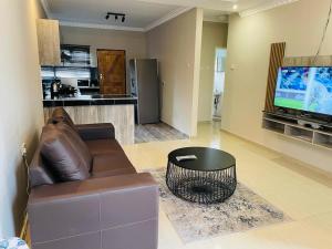 sala de estar con sofá, mesa y TV en Rocksie Apartments en Maun