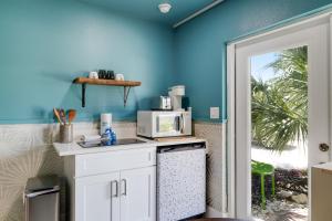 a kitchen with blue walls and a counter with a microwave at Pirates Retreat Cottage at Palmview Inn of Sanibel in Sanibel