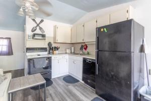 a kitchen with a black refrigerator and white cabinets at Bungalow 1 minute from the beach suite #5 in Englewood