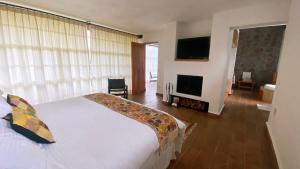 a bedroom with a white bed and a television at Cabin Manzana Nature Retreat with amenities in Zitácuaro