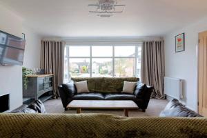 a living room with a couch and a large window at Wilshere House in Kirby Muxloe