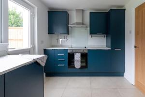 een keuken met blauwe kasten en een fornuis bij Wilshere House in Kirby Muxloe