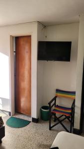 Habitación con puerta, silla y TV. en Hotel La Avenida, en Guatapé