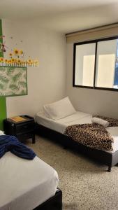 a room with two beds and a window with a leopard print bed at Hotel La Avenida in Guatapé