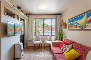 Una sala de estar con un sofá y una ventana. en Apto tranquilo a 3min da praia Canasvieiras FML202, en Florianópolis