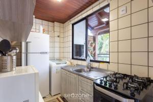 Una cocina con estufa, fregadero y ventana. en Apto tranquilo a 3min da praia Canasvieiras FML202, en Florianópolis 8 fotos más