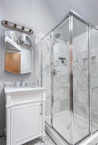 ein weißes Bad mit einer Dusche und einem Waschbecken in der Unterkunft City Park Casita Walk To Eats Brews Park More in Denver