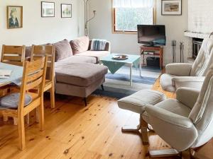 sala de estar con sofá, sillas y TV en Holiday home ARILD III, en Arild