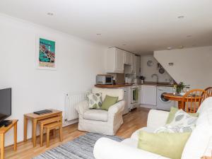 a living room with a couch and chairs and a kitchen at Wisteria Cottage in Exmouth