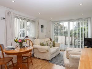 a living room with white furniture and a table at Wisteria Cottage in Exmouth