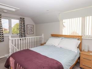 a bedroom with a bed with white walls and windows at Wisteria Cottage in Exmouth