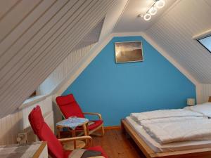 a attic bedroom with a bed and two chairs at Ferienhaus Zum Storchennest in Storkow in Storkow