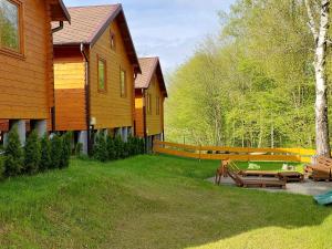 a wooden house with benches in front of it at Domki Pod Jaworem in Solina