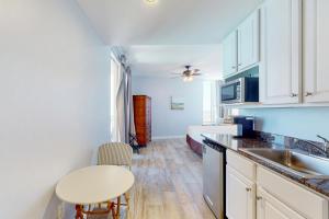 a kitchen with white cabinets and a sink and a table at Splash Resort 1901W Suite A Studio in Panama City Beach