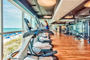 einen Fitnessraum mit einer Reihe von Laufbändern und dem Strand in der Unterkunft Splash Resort 1901W Suite A Studio in Panama City Beach
