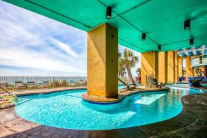 a swimming pool in a resort with the ocean in the background at Splash Resort 1901W Suite A Studio in Panama City Beach