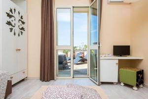 a room with a sliding glass door with a desk and a television at Approdo Boutique Hotel Leuca in Leuca