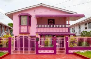 uma casa cor-de-rosa com uma cerca roxa à frente. em Casa Rosa em Georgetown