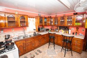 a kitchen with wooden cabinets and bar stools at Casa Rosa in Georgetown