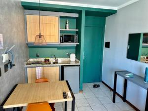 - une cuisine avec des murs verts et une table avec des chaises dans l'établissement Flat Vista para o Mar/Piscina/Cama Queen/Ar, à Vitória