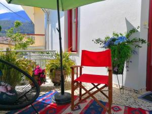 a red chair sitting under an umbrella on a patio at Thalgiron, a breath away from Delphi in Ámfissa