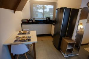 a kitchen with a black refrigerator and a table at Cabana Mulungu - Viagem Inspirada in Fernando de Noronha