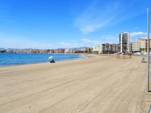 a person sitting on a beach with an umbrella at Apartamento céntrico junto paseo, playas y zonas de interés!! in Águilas