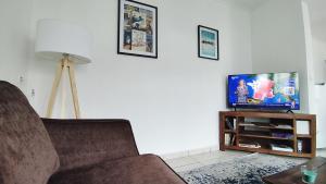 a living room with a couch and a flat screen tv at Charmante Maison T2 de plein pied avec extérieur calme aux Arènes in Béziers