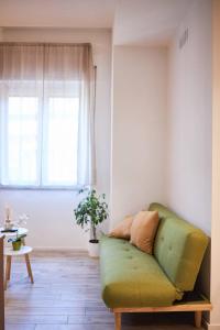 a living room with a green couch and a window at Plebiscito House in Castel di Sangro