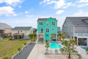 a green house with a pool in front of a house at Key Rest in Oak Island