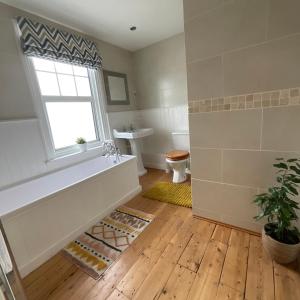 a bathroom with a tub and a toilet and a window at The Sandgate Cottage in Sandgate