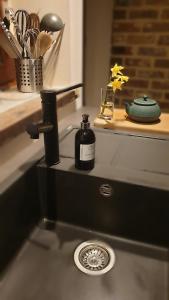 een wastafel in de badkamer met een zeepdispenser op een aanrecht bij Le basecamp des sommets in Stavelot