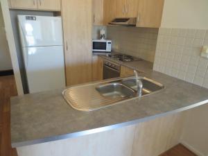 a kitchen with a sink and a refrigerator at Holdfast Shores Apartments in Adelaide