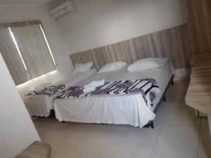 2 camas en una habitación de hotel con faldas en HOTEL TOPAZIO, en Cristalina