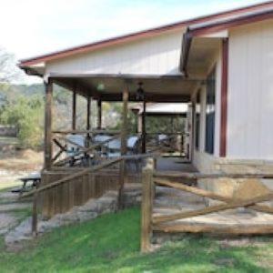 ein Haus mit einem Holzzaun davor in der Unterkunft Thunderbird Lodge in Burnet