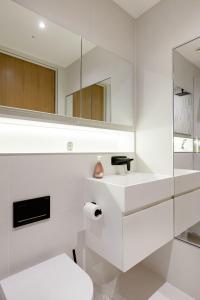 ein weißes Badezimmer mit einem Waschbecken und einem Spiegel in der Unterkunft Modern Apartment & Rooms at Charing Cross in London