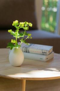 un jarrón con flores en una mesa con dos libros en Rückzugsort mitten im Paradies en Feldafing