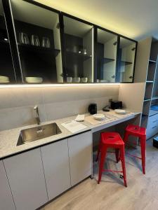 a kitchen with a sink and two red stools at Moderno departamento vanguardista en el corazón de Las Condes in Santiago