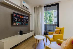 a living room with a tv and yellow chairs at Live Soho Boutique & Apartments Palermo Soho II in Buenos Aires