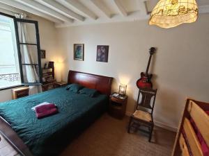 a bedroom with a bed and a guitar on the wall at Charmante et spacieuse maison de village in Courdemanche
