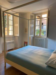 a bedroom with a canopy bed with two windows at CAPI SUITE in Griante Cadenabbia