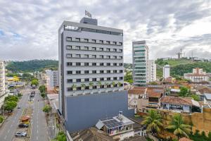 a tall white building with plants on it in a city at HOTEL GRAN PREMIUM PLAZA LTDA in Muriaé