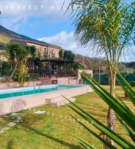 een villa met een zwembad en een palmboom bij CASA VACANZE FONDACO DI SCILLATO in Scillato