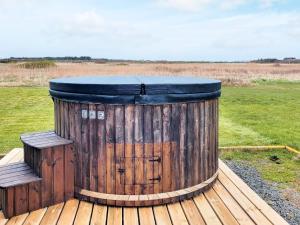 a wooden barrel sitting on a deck in a field at 4 person holiday home in Harbo re in Harboør
