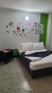 a bedroom with a bed with flowers on the wall at Hotel La Avenida in Guatapé