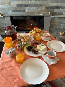 una mesa con platos de comida en una mesa con chimenea en 3 VELLEZERIT DOCI GUEST HOUSE, en Fushë-Lurë