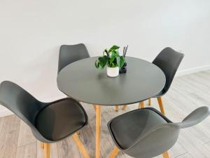 einem weißen Tisch mit vier Stühlen und einer Topfpflanze in der Unterkunft Unique 2 bedroom Apartment 15 mins via tube to Central London in London